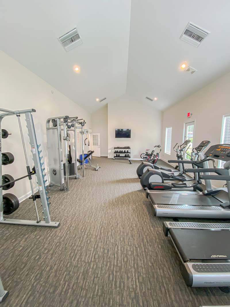 fitness room with treadmills, elliptical machines, and weights